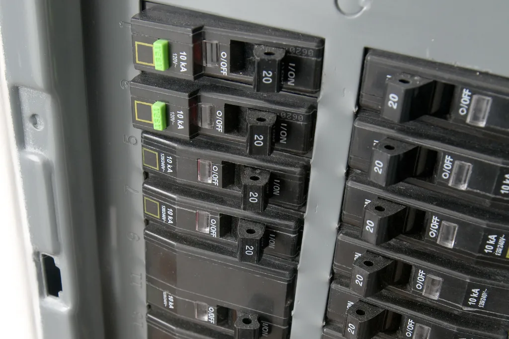 A close-up of an electrical breaker panel with multiple circuit breakers, showing the importance of managing electrical loads to prevent overloaded circuits.