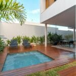 A serene modern patio featuring a luxurious hot tub, chic furniture, and lush greenery.