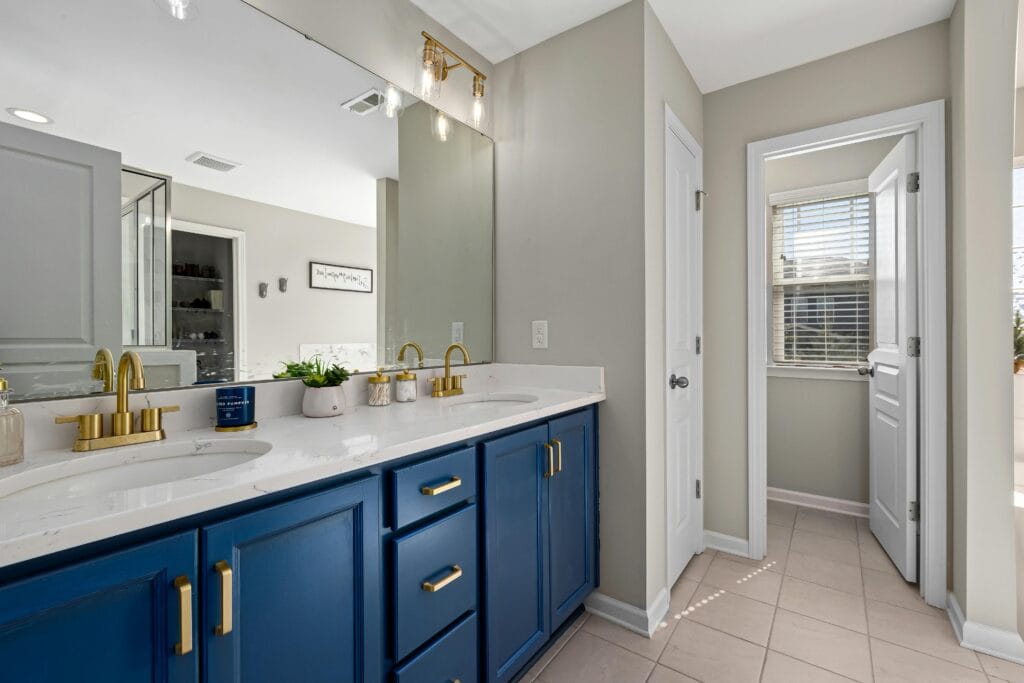 Bathroom featuring a blue vanity, gold fixtures, and decorative accents for a modern home interior and electrical upgrade
