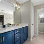 Bathroom featuring a blue vanity, gold fixtures, and decorative accents for a modern home interior and electrical upgrade